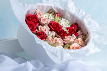 Beautiful arrangement of marshmallow flowers in a white round box, featuring vibrant red, soft pink, and delicate white blooms, showcasing unique floristry concept with copy space