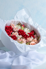 Beautiful arrangement of marshmallow flowers in a white round box, featuring vibrant red, soft pink, and delicate white blooms, showcasing unique floristry concept with copy space