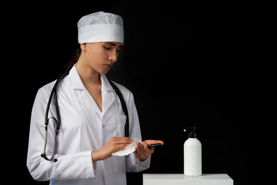 disinfection of the phone with a sanitizer. the doctor disinfects and wipes the smartphone with napkin. copy space on black background