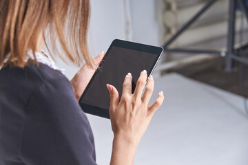Young caucasian woman using tablet indoors with touchscreen technology focus.