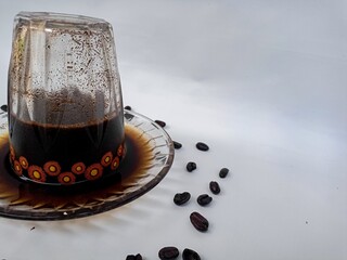 Freshly brewed black coffee served in an inverted cup with coffee beans spread around, representing lifestyle and cafe culture.