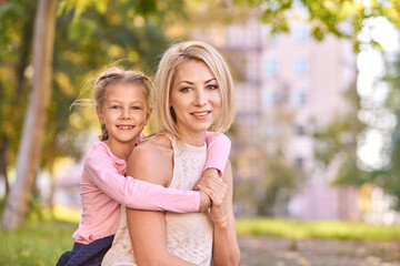 Fototapeta premium Happy caucasian mother and daughter outdoors in park smiling together.