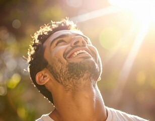 Joyful man smiling and looking up at bright sunlight in nature