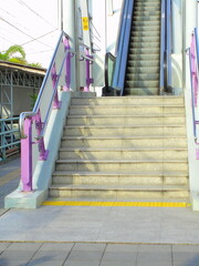 A staircase with purple railings leads up to a skytrain platform, captured in vintage retro tones with film grain.
