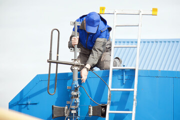 Male technician installing antenna on rooftop with ladder and equipment.