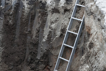 Ladder in deep excavation site with exposed earth layers.