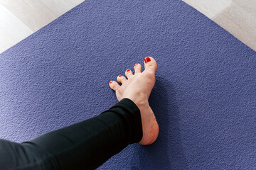 Yoga woman stretching feet spreading her toes doing toe stretch on exercise mat
