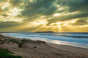 Photograph of a dramatic and vibrant sunrise on Warilla Beach on the South Pacific Ocean coastline in the Illawarra region of NSW, Australia.