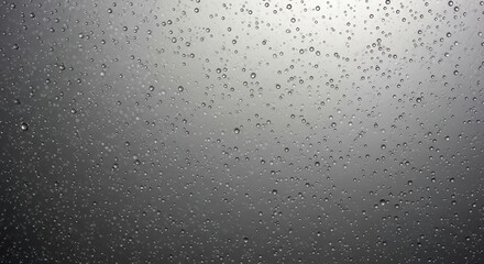 Obraz premium A close-up view of water droplets from rain or condensation beaded on a smooth gray surface.