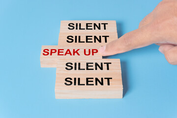 Finger pointing at wooden block with word speak up. Courage to speak up concept
