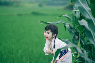 A joyful girl enjoying nature in a green field, wearing a white top and smiling.