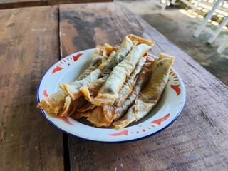 Serving chocolate bananas on an antique iron plate, on a wooden table, menu in a cafe with an outdoor concept.