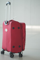 Red suitcase with wheels placed on modern airport floor
