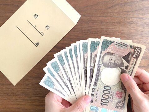 机上の給料袋と紙幣を持つ女性の手