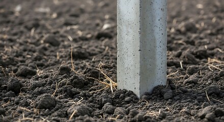 Concrete Post in Brown Soil Field.