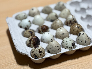 Fresh quail eggs in a tray top view on a wooden table ready for sale. Quail eggs arranged on the egg tray. Raw quail eggs on a culinary background. The concept of proper nutrition, healthy lifestyle. 