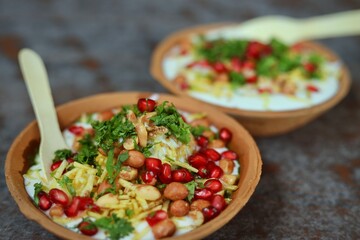 Indian Chaat Dahi Bhalle with Curd and Sweet Sauce on banana leaf with indian backdrop