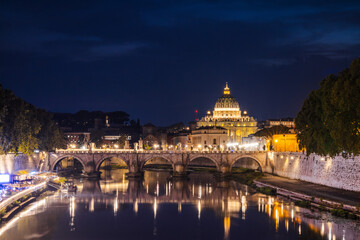 Illuminated St. Peter's Basilica in Vatican City with the glowing Ponte Sant'Angelo bridge...