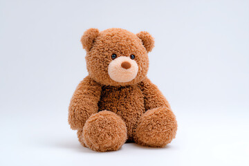 Obraz premium A soft, brown teddy bear with a round face, black eyes, and a light brown snout sits against a plain white background, evoking warmth and childhood comfort