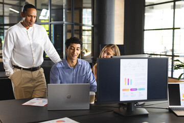 Business team collaborating on project with laptops and charts in modern office