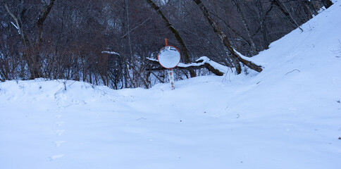 雪に埋もれたカーブミラー