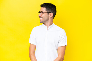 Young handsome man over isolated yellow background looking side