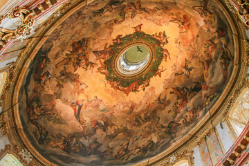A breathtaking Baroque fresco painting on a church dome in Vienna, depicting a celestial ascent of figures towards a central oculus, surrounded by ornate gold details