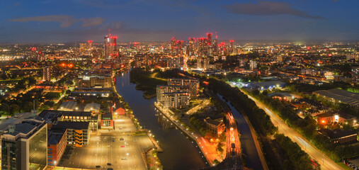 Twilight aerial panorama of Manchester skyline with River Irwell, canals, Pomona Strand, and illuminated cityscape.