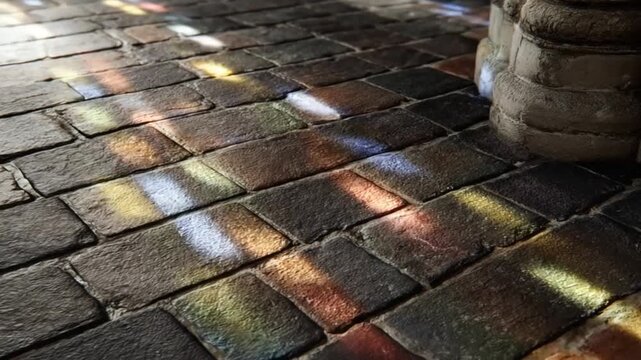 Colorful stained glass light patterns illuminating a stone pavement.