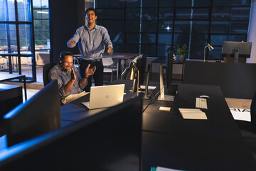Colleagues celebrating success at office, working late with laptop and headphones