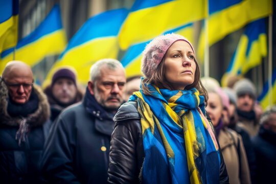 Woman wearing blue and yellow scarf stands focused among crowd at rally, with vibrant flags of Ukraine waving in background, capturing essence of unity and solidarity in atmosphere - Powered by Adobe
