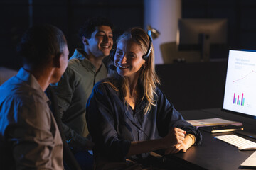 Team collaborating at office, smiling and discussing data on computer screen