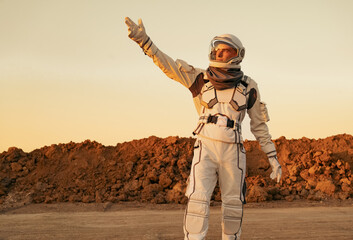 An astronaut extending his hand forward on an alien planet, symbolizing exploration and discovery.