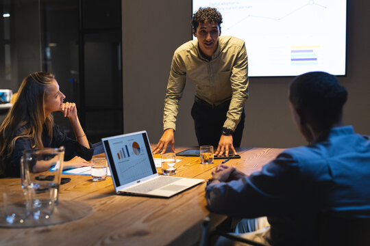 Businessman presenting data to colleagues in conference room during night meeting