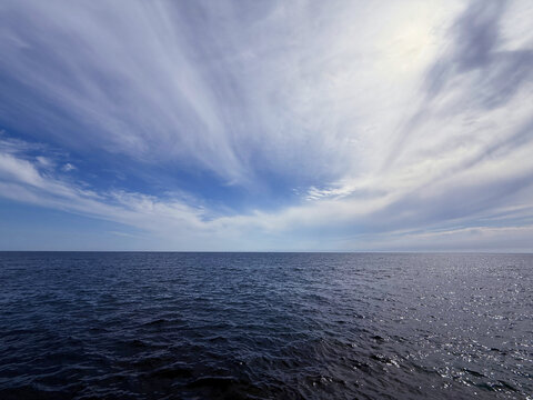 Cloudy sky over dark blue glittering sea.