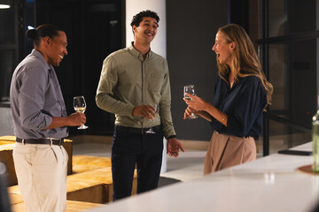 Networking at office event, professionals conversing and holding wine glasses