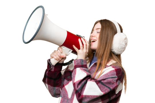 Young pretty woman wearing winter muffs over isolated chroma key background shouting through a megaphone