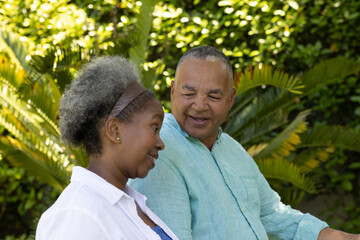 In park, African American senior couple talking surrounded by lush greenery