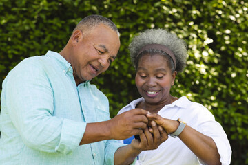 Senior African American couple smiling while looking at smartphone outdoors