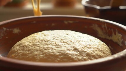Rising dough in terracotta bowl, soft focus in natural light. - Powered by Adobe