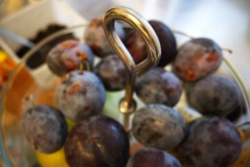 Close-up of fresh plums arranged in a transparent glass serving bowl. Healthy fruit concept.