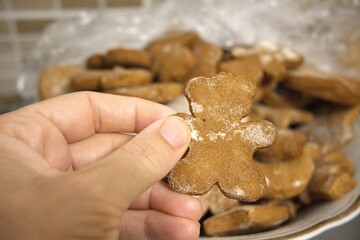 Close-up of traditional homemade gingerbread cookies served on a plate with hand. Christmas festive concept with cozy holiday mood.