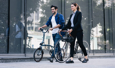 Commuting to work with bicycle. Businessman businesswoman cycling to office in downtown district. Modern diverse people use eco transportation on city street. Environmental pollution, climate change.
