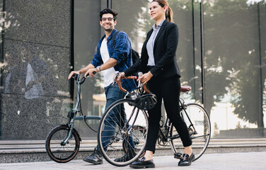 Obraz premium Commuting to work with bicycle. Businessman businesswoman cycling to office in downtown district. Modern diverse people use eco transportation on city street. Environmental pollution, climate change.