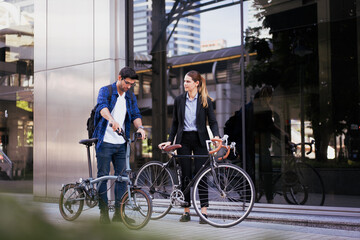 Obraz premium Commuting to work with bicycle. Businessman businesswoman cycling to office in downtown district. Modern diverse people use eco transportation on city street. Environmental pollution, climate change.