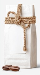 A pristine white paper bag, tied with natural twine, sits on a white background, two coffee beans rest in front