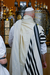 A father standing by the Torah during a Bar Mitzvah of his boy 