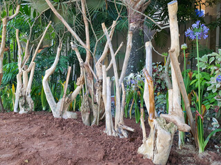 AI image: Driftwood art installation amidst lush tropical foliage and blooming blue flowers in
