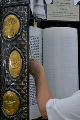 A bar mitzvah boy reading from the Torah scroll in a synagogue.