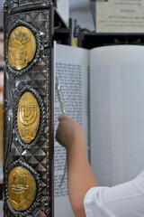 A bar mitzvah boy reading from the Torah scroll in a synagogue.